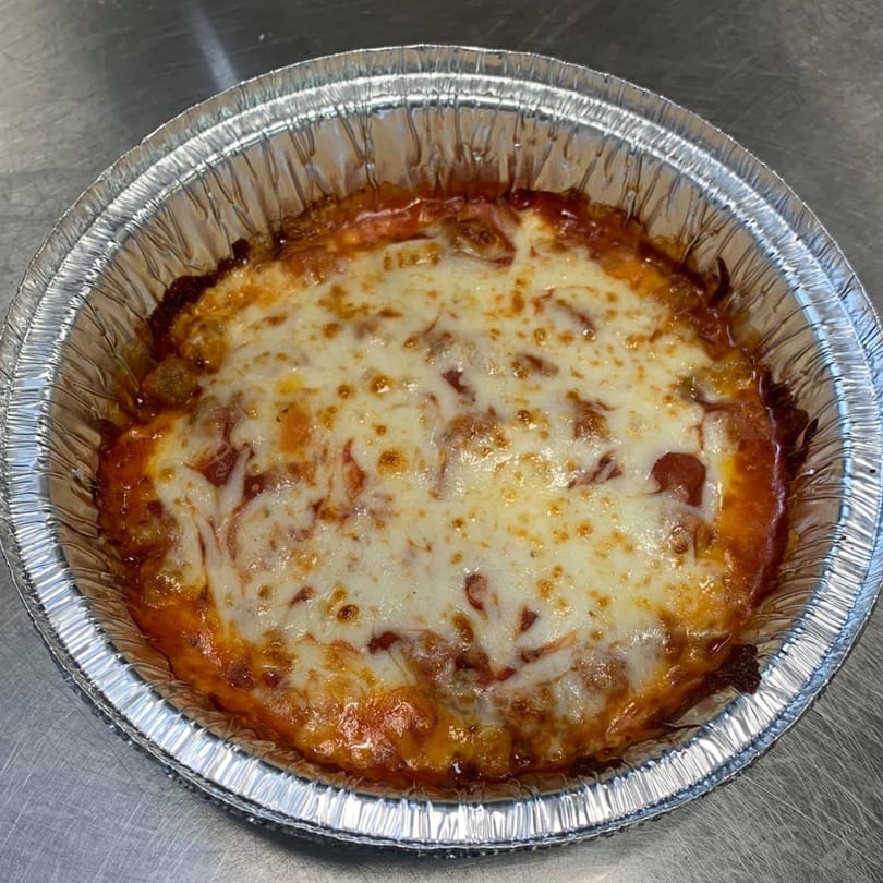 Spinners Pizza & Pasta's baked pasta dish with melted cheese and red sauce in a foil container.
