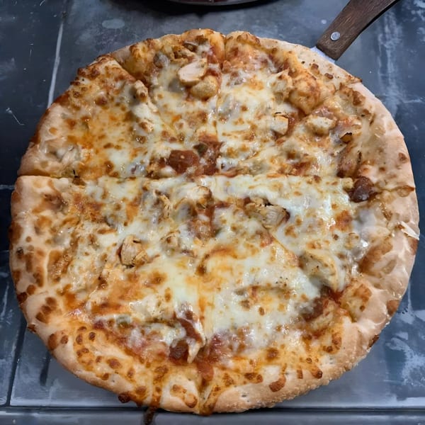 A freshly baked chicken pizza from Spinners Pizza & Pasta, with melted cheese and a crispy crust.